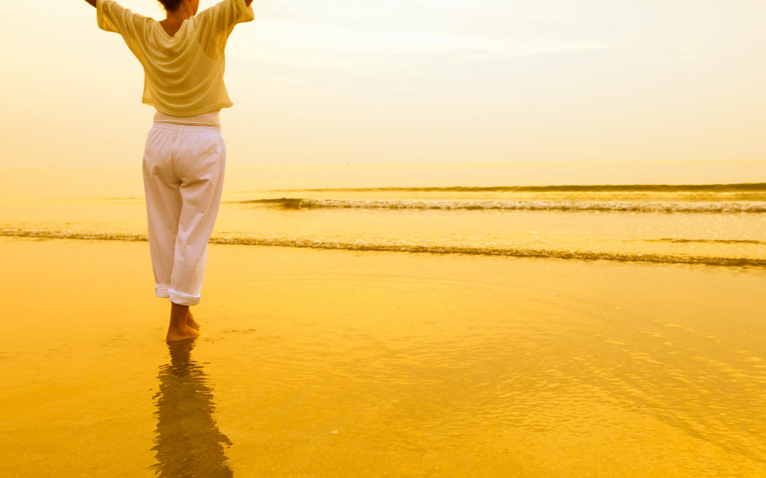 Photo of woman joyful on a sunrise beach with her arms raised in the air